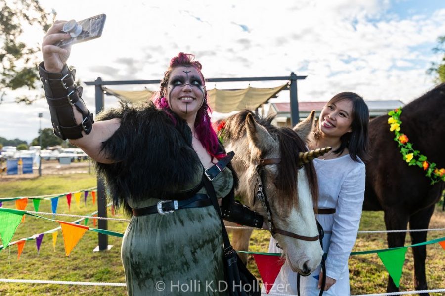 A woman in viking costume taking a selfie with a unicorn
