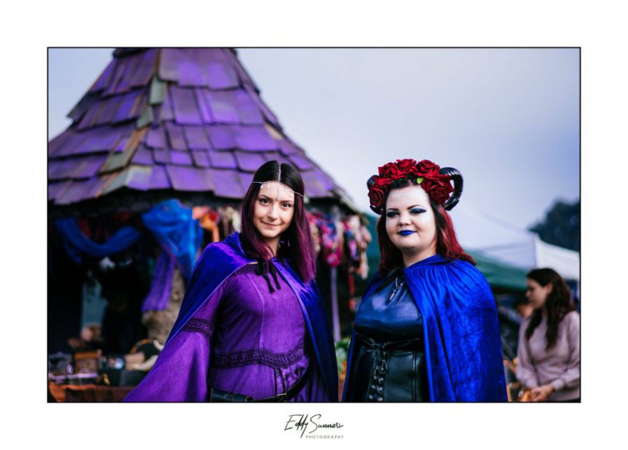 Two women in fantasy costumes in front of a witch hut