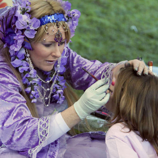 A child having their face painted by a fairy at Winterfest